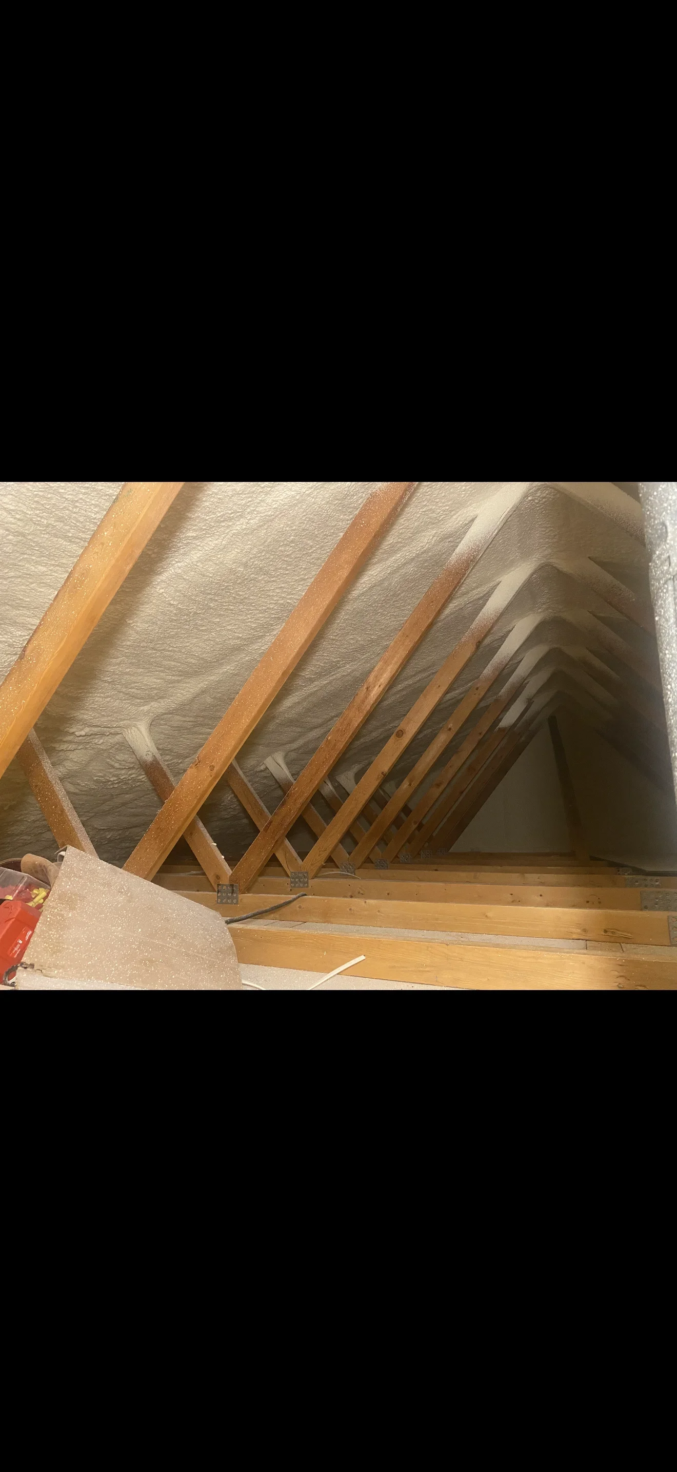 Spray foam insulation applied to attic rafters and ceiling joists with wood framing