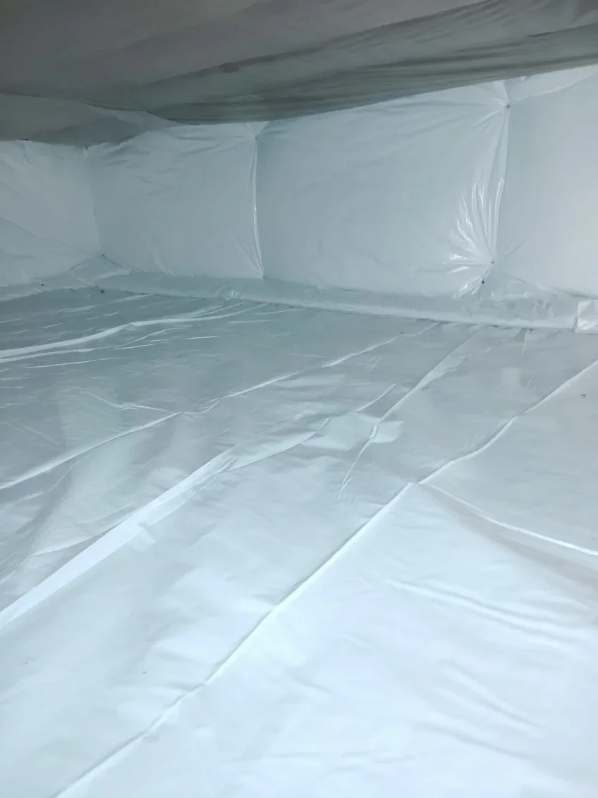 Crawl space with white polyethylene vapor barrier installed on floor and walls