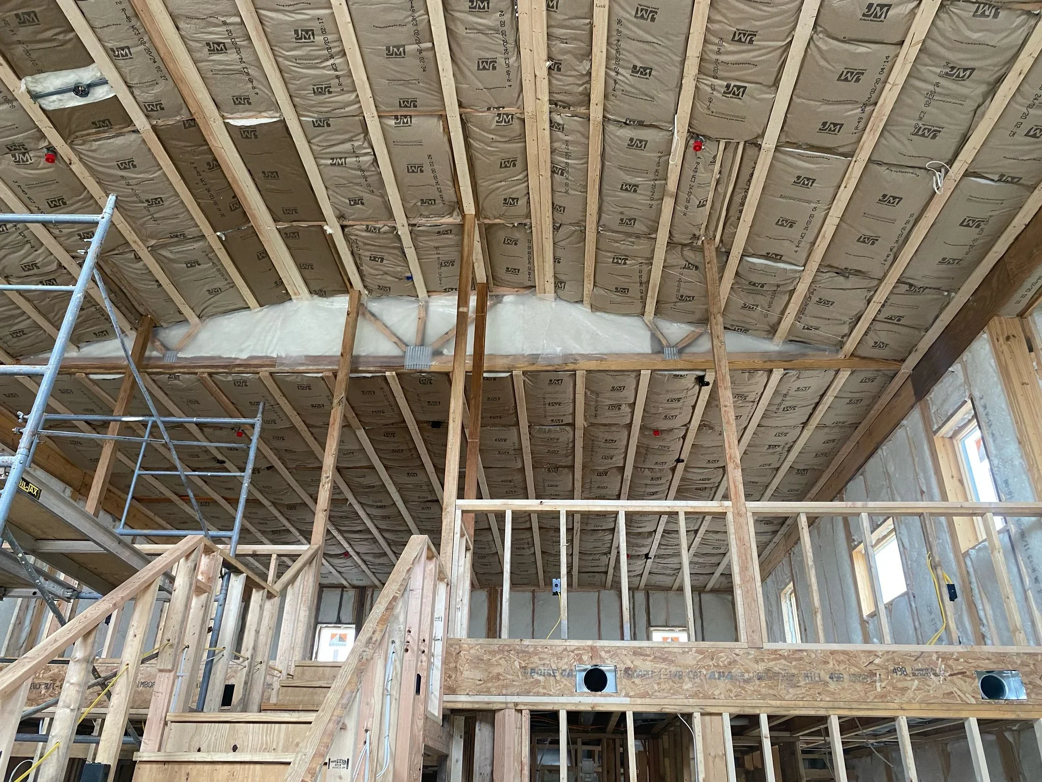 Attic insulation installation with kraft-faced fiberglass batts between wood framing and rafters