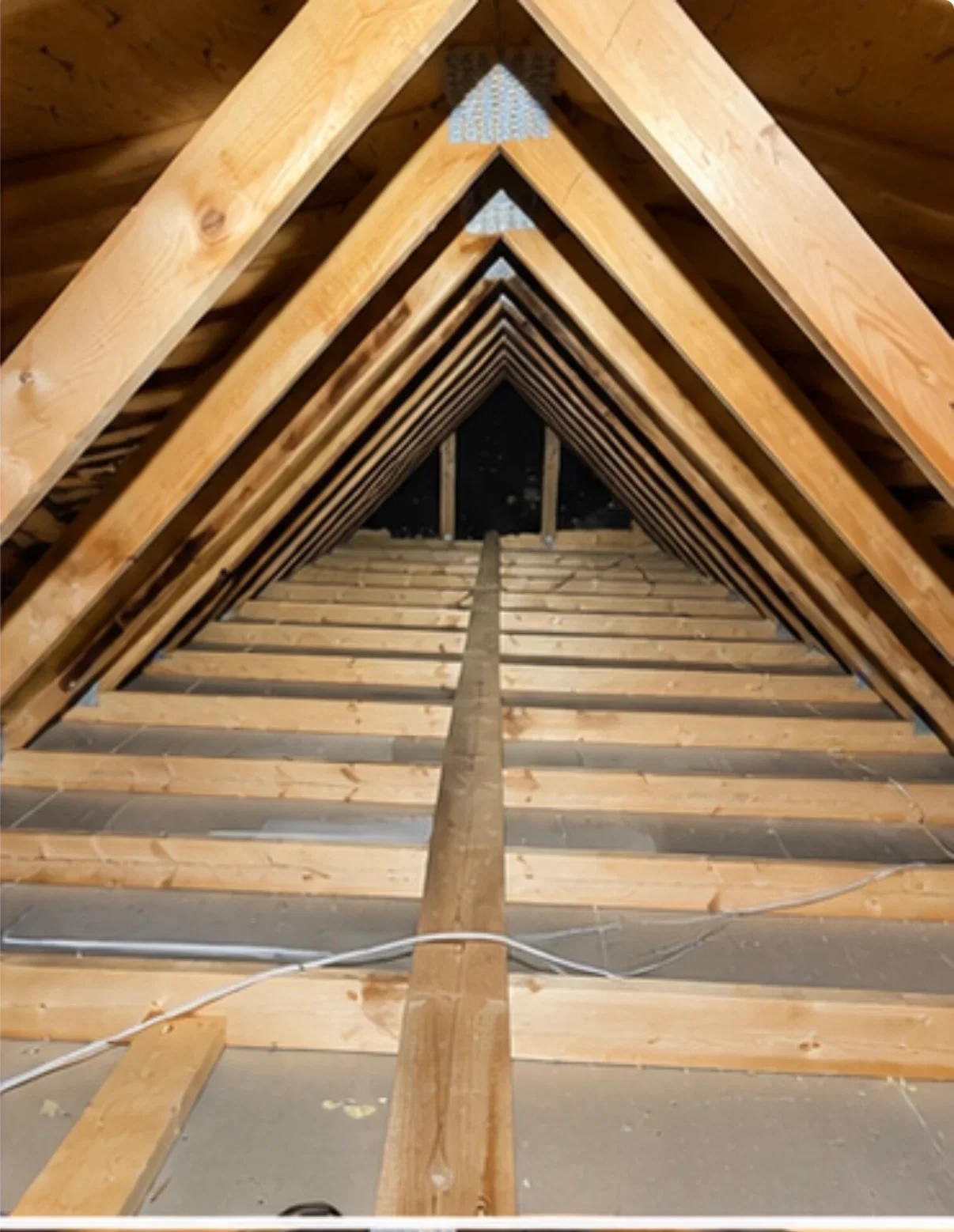 Attic framing with installed fiberglass insulation batts between wooden joists and ventilation setup