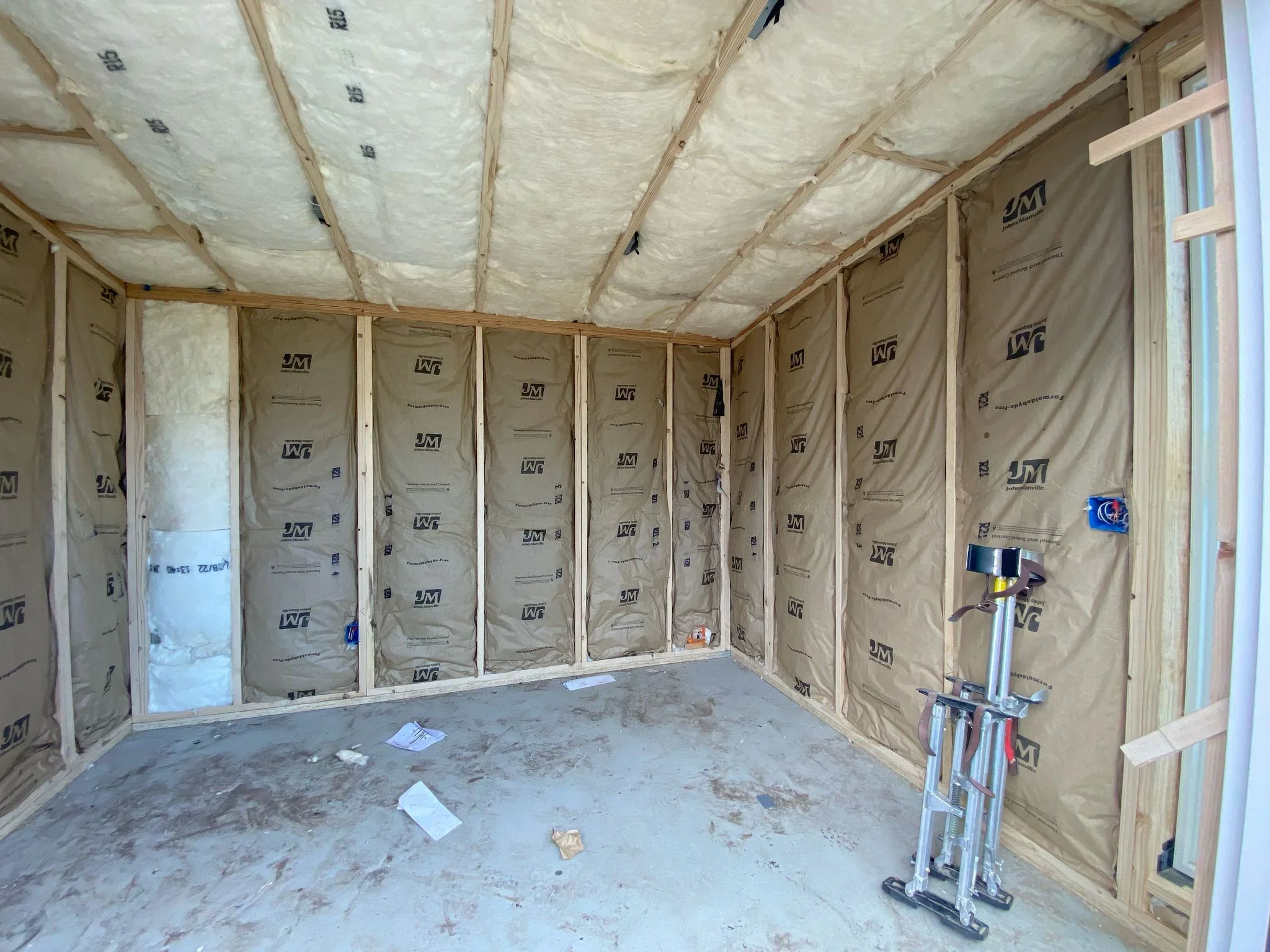 Fiberglass batt insulation installed in wall cavities and ceiling with kraft facing and vapor barrier